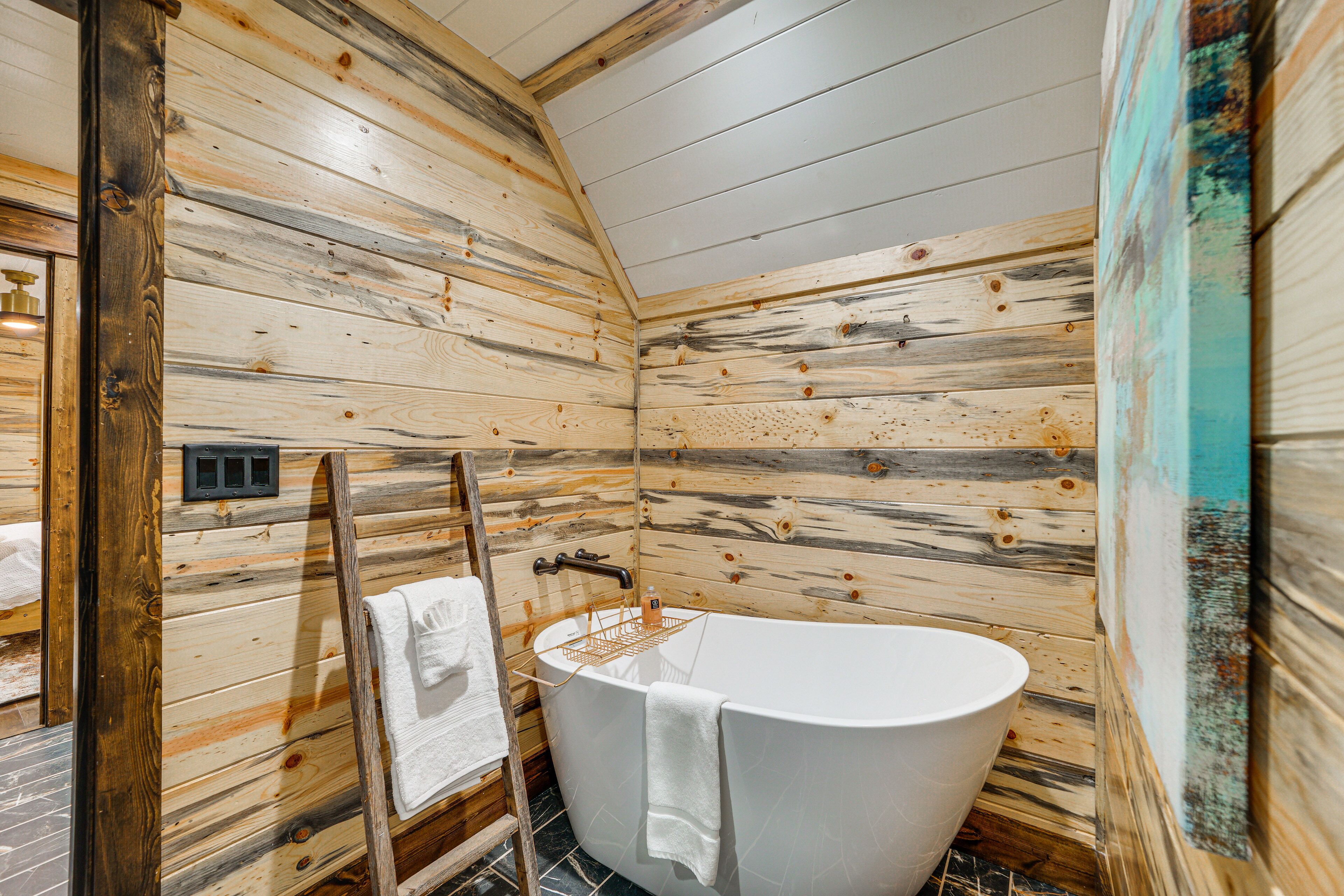 A wooden cabin bathroom with a freestanding bathtub, a towel rack, and a wooden ladder.