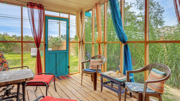 A covered patio with wooden flooring, a table, chairs, and a door leading outside. - New Mexico Cottage: Private Yard & Hot Tub (Truth or Consequences)