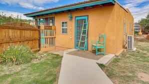 A single-story building with a blue door and windows, a wooden fence, and a small porch area. - New Mexico Cottage: Private Yard & Hot Tub (Truth or Consequences)
