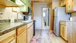 A kitchen with wooden cabinets, a stainless steel refrigerator, and a granite countertop. - New Mexico Cottage: Private Yard & Hot Tub (Truth or Consequences)