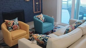 A living room with a fireplace, a blue armchair, a yellow armchair, and a white sofa. - Tropical Pool & Spa Home, 3/2, Near Disney, Universal, Sea World, Beaches (Altamonte Springs)