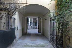 A narrow alleyway with a tiled floor, flanked by walls and a metal gate on one side. - Custodi Studio Apartment (Milano)