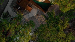 An aerial view of a circular building surrounded by dense forest.