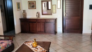 Un salon avec un meuble en bois, un tapis à motifs et un lit recouvert d’une couverture colorée.