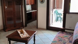 Un salon avec un meuble en bois, une petite table sur laquelle est posé un vase, et un canapé aux couleurs vives.