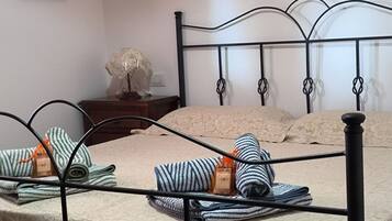 A neatly made bed with striped bedding and a decorative lamp on a wooden nightstand.