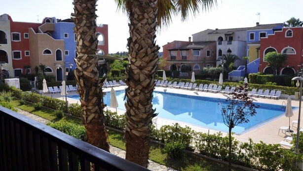 A pool area with lounge chairs and palm trees. - BORGO SAN BASILIO APPARTAMENTO PENELOPE-CON PISCINA E ANIMAZIONE DIURNA E SERALE (Pisticci)