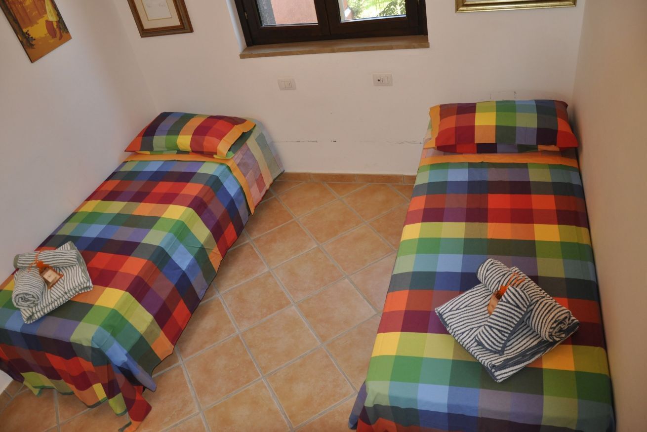 A room with two beds, each with a colorful checkered bedspread and pillows.
