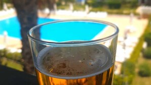A glass of beer with a clear view of a swimming pool in the background. - BORGO SAN BASILIO APPARTAMENTO PENELOPE-CON PISCINA E ANIMAZIONE DIURNA E SERALE (Pisticci)