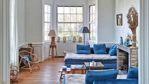 A cozy room with a blue sofa set, wicker chairs, a small table, and a fireplace.