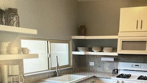 A kitchen with a central island, a stove, a microwave, and bar stools. - Comfortable safe gated community, located 12 min away from Valle de Guadalupe. (El Sauzal)