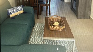 A living room with a sofa, a coffee table, and a dining area with chairs and a table. - Comfortable safe gated community, located 12 min away from Valle de Guadalupe. (El Sauzal)