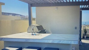 An outdoor patio with a grill, bar stools, and a view of the ocean. - Comfortable safe gated community, located 12 min away from Valle de Guadalupe. (El Sauzal)