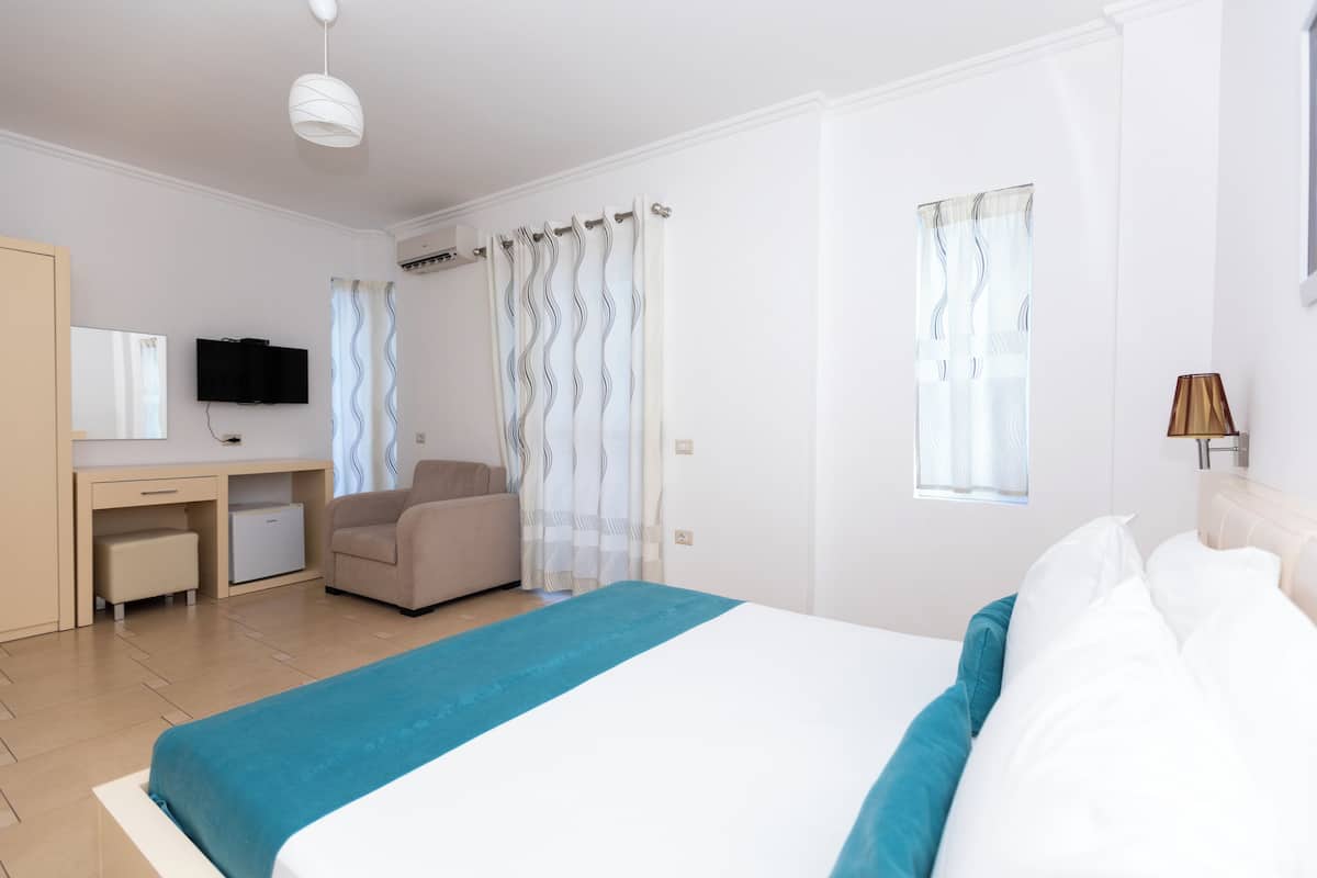A hotel room with a bed, a desk, a chair, a television, and a window with curtains.