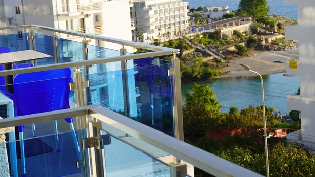 Un hotel moderno con balcón de vidrio que ofrece vistas a la costa, con piscina y vista al mar.