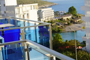 A modern hotel with a glass balcony overlooking a coastal area, featuring a pool and a view of the sea. - Hotel AGEL (Sarandë)