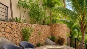 A pool area with two chairs, a stone wall, and tropical plants. - Beach frontage Family Vacation home, 10 miles from downtown PV romantic zone (Boca de Tomatlán)