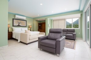 Une chambre à coucher comprenant un lit, deux canapés, un fauteuil, une table de chevet, un appareil de climatisation et une fenêtre donnant sur les montagnes.