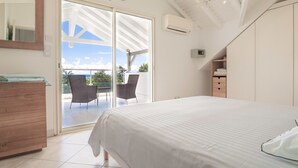 Ein Schlafzimmer mit einem großen Bett, einer Holzkommode, einem Spiegel und einem Balkon mit Stühlen.