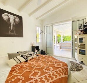Un dormitorio con cama, almohadas, mesita de noche, lámpara, armario y un amplio ventanal con vistas a zonas verdes.