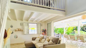 Ein geräumiges Wohnzimmer mit einer großen, beigefarbenen Couch, einem kleinen runden Tisch und einem Balkon mit Sitzgelegenheit.