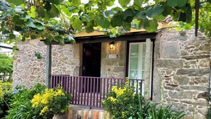 A stone building with a stone bench, a wooden door, and a sign that reads 'Casa Velha.'