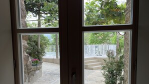 A view through a multi-pane window with stone walls and a white fence.