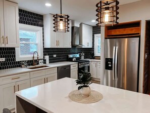 A modern kitchen with white cabinets, a stainless steel refrigerator, and pendant lighting. - Hot Tub - Sleeps 8 - Pet Friendly - Cleveland (Cleveland)