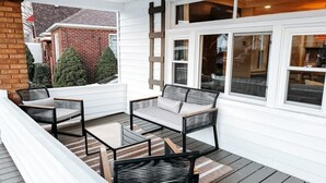 Un espace extérieur aménagé, abrité et doté d’un canapé et de fauteuils, d’une petite table et d’une terrasse en bois.