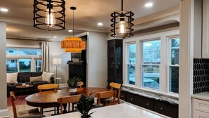 Une cuisine moderne dotée d’un îlot central, de luminaires suspendus et offrant une vue sur l’extérieur.