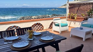 An outdoor patio with a table set for dining, overlooking the ocean. - Raffaela's House (Massa Lubrense)