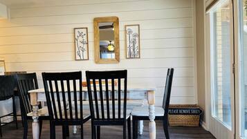 Un coin repas avec un mur en bois peint en blanc, un miroir encadré en bois et deux œuvres d’art florales encadrées.