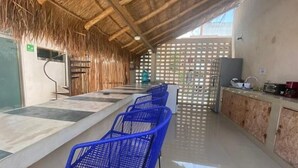 A long counter with blue chairs, a kitchen area with a wooden cabinet, and a straw-thatched ceiling. - Hotel downtown Cancun, great location! Private room. (Cancún)