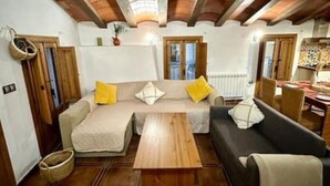 Uma sala de estar acolhedora com um sofá, uma mesa de centro de madeira e uma área de jantar com mesa e cadeiras.