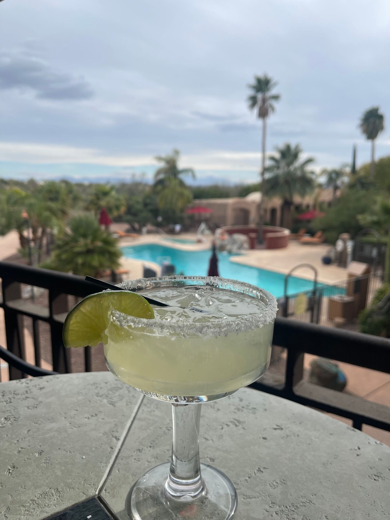 A margarita on a table with a pool view.