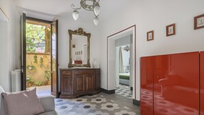A room with a sofa, a mirror, a cabinet, a red wardrobe, and a hexagonal patterned floor.