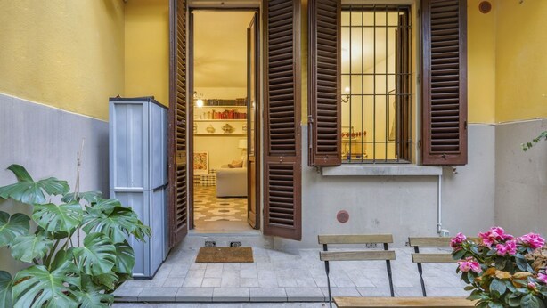 An open door leading to a room with a tiled floor, a bench, and a potted plant.