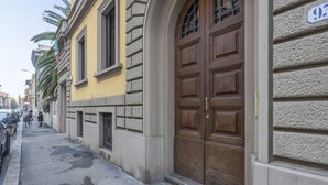 A street view with a yellow building, a large wooden door, and parked cars.