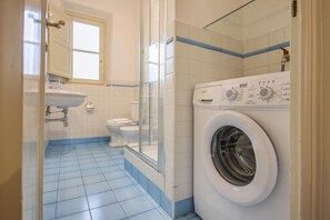 Une salle de bain équipée d’un lave-linge, d’un lavabo et de toilettes.