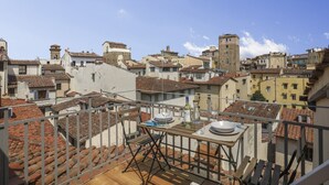 A rooftop terrace with a table set for dining, surrounded by terracotta-tiled buildings.