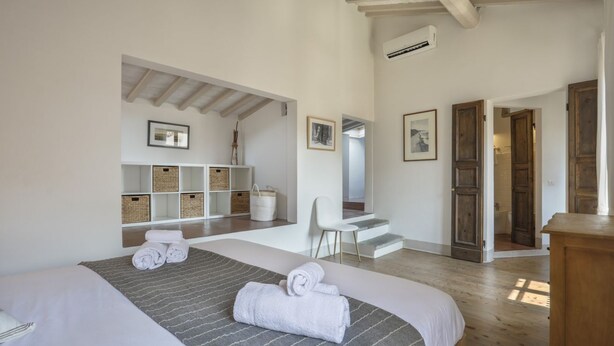 A bedroom with two beds, a desk, and a chair. There are baskets on shelves and a wooden door.