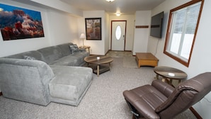A living room with a grey sectional sofa, a brown leather chair, a coffee table, a small wooden table, and a TV mounted on the wall. - Minutes from downtown Wisconsin Dells and sports and water parks.  (Wisconsin Dells)