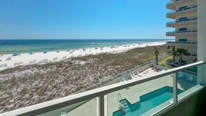 Un balcón de hotel con vista a una playa y una piscina.