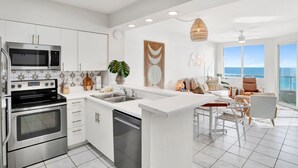 Una cocina moderna con electrodomésticos de acero inoxidable, una isla central con pileta y un comedor con vista al océano.
