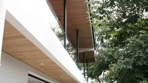 A modern house with a swimming pool, outdoor seating, and a surfboard leaning against the wall.