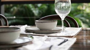 A dining table with a glass, bowl, and plates set for a meal.