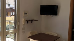 A room with a dining table and chairs, a mounted TV, and a sliding glass door leading to an outdoor area. - Apartment by the sea with swimming pool (Porto Empedocle)