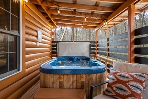 A wooden cabin with a hot tub, wooden walls, and a window.