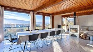 A spacious dining area with a long table and chairs, a fireplace, and large windows offering a mountain view. - Awesome home in Talloires-Montmin (Talloires-Montmin)