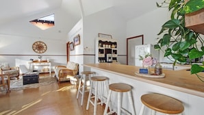 Una cocina moderna con barra, taburetes blancos y espacio para café.